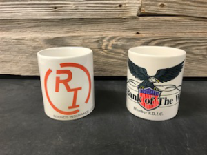 Two logoed coffee mugs on wood background